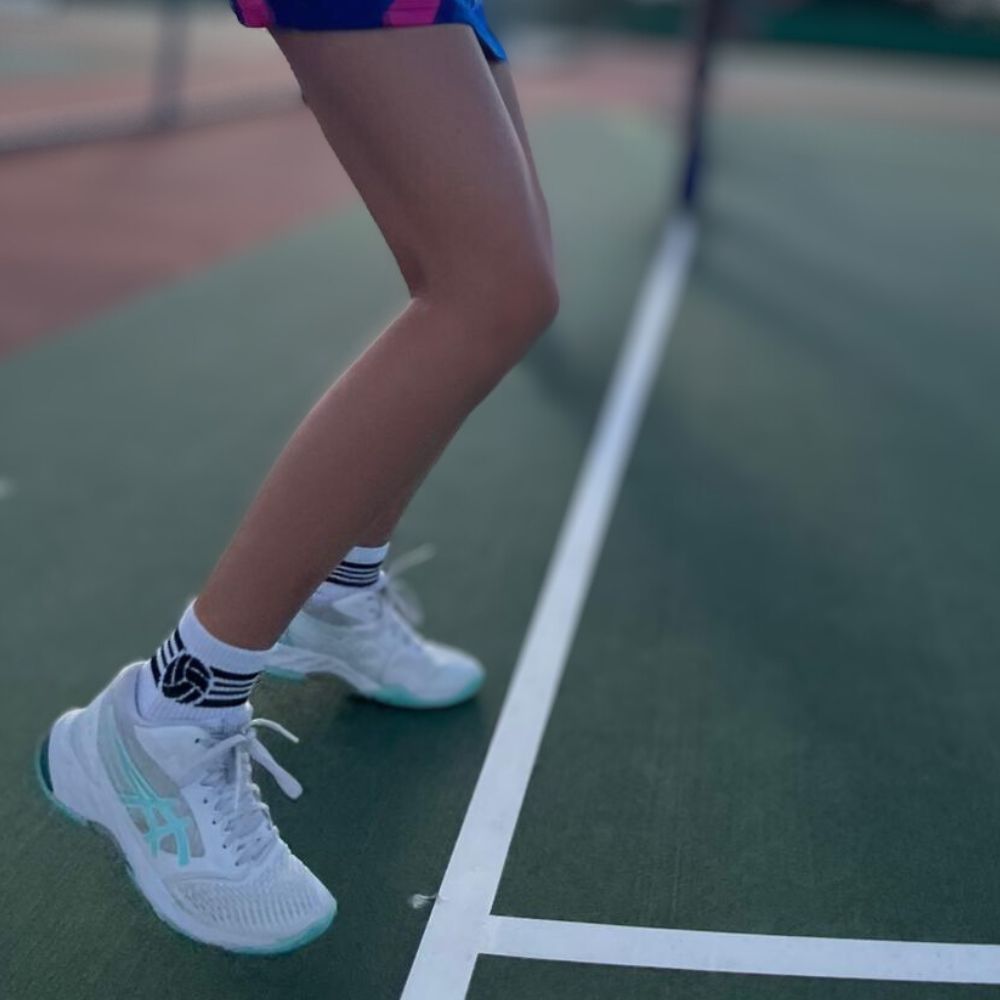 Netballer on side of court doing dynamic warmup in Shoot white quarter crew netball socks
